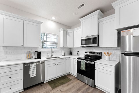 A white kitchen with a refrigerator on the right.