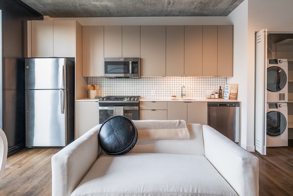 a living room with a couch and a kitchen with stainless steel appliances