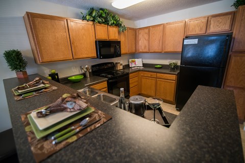 A kitchen with wooden cabinets and a black refrigerator.