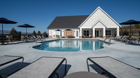 Resort-style pool with ample seating, lounge chairs and umbrellas.