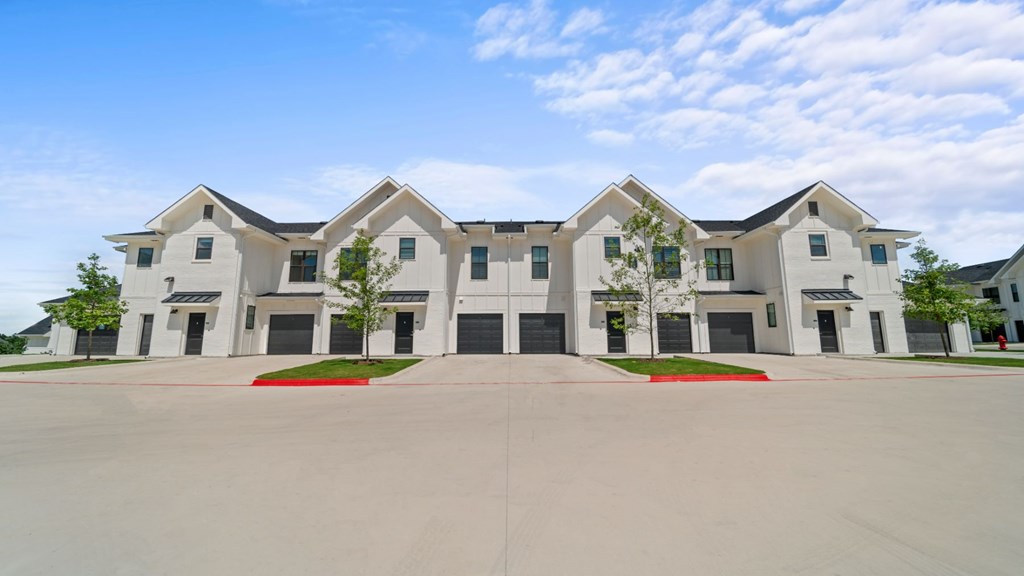 the exterior of a large apartment building with a parking lot
