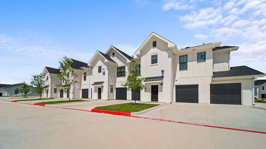 a row of town homes with black and white doors and a driveway