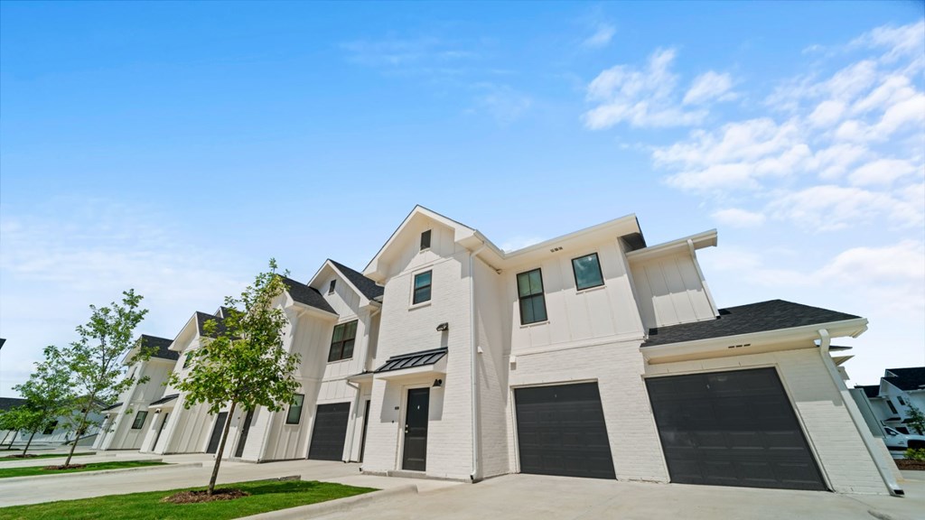 a group of white houses with black garage doors