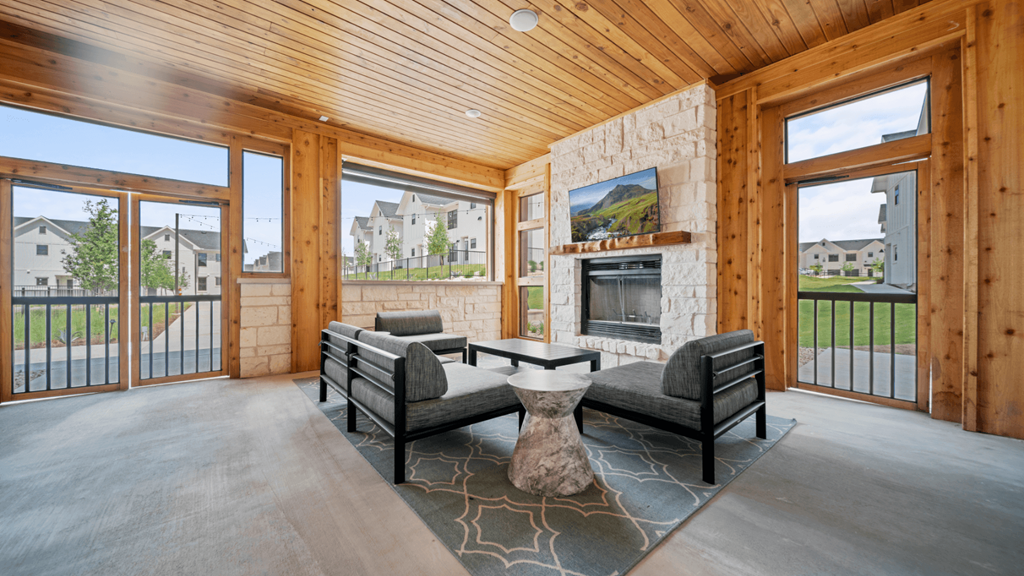 the living room of a home with a stone fireplace and chairs