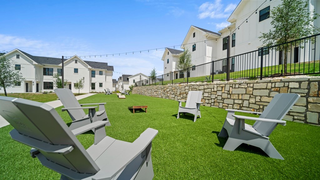 a backyard with lounge chairs and a fire pit