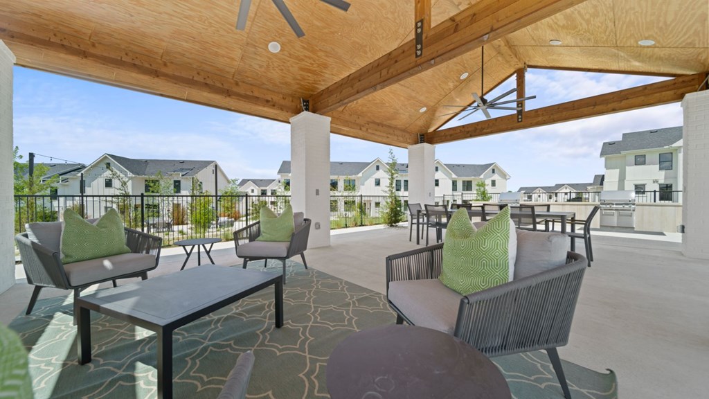 a patio with chairs and tables and a wooden roof