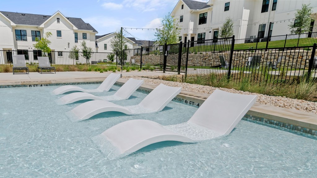 a resort style pool with white chaise lounges