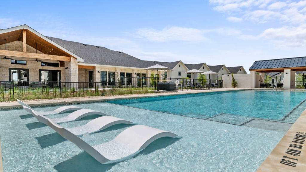 a swimming pool with two lounge chairs in front of a house