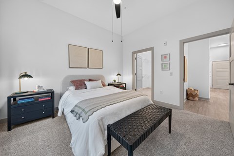 A bedroom with a bed, nightstand, and a bench.