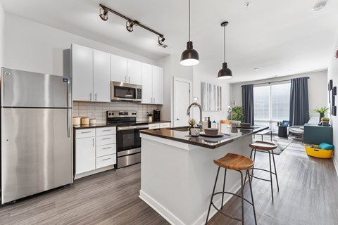 A modern kitchen with a stainless steel refrigerator and wooden bar stools.