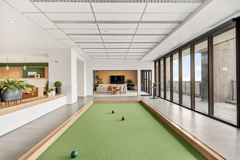 A room with a green carpet and a pool table.