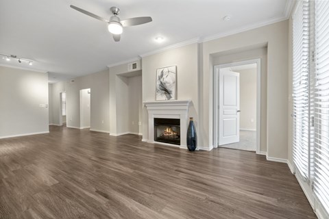 A spacious room with a fireplace and wood flooring.