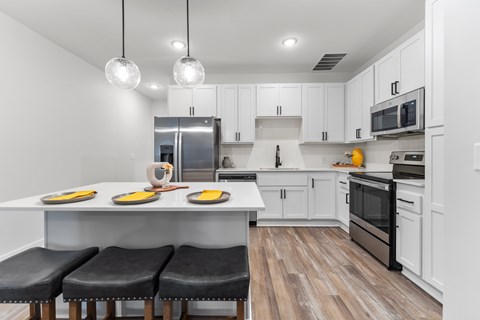 A modern kitchen with a white table and black stools.