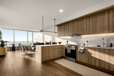 A modern kitchen with wooden cabinets and a large window overlooking the ocean.