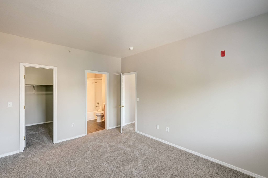 a bedroom with a carpeted floor and a door to a bathroom