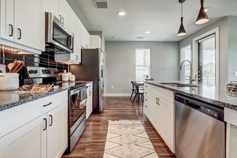 A modern kitchen with white cabinets and stainless steel appliances.