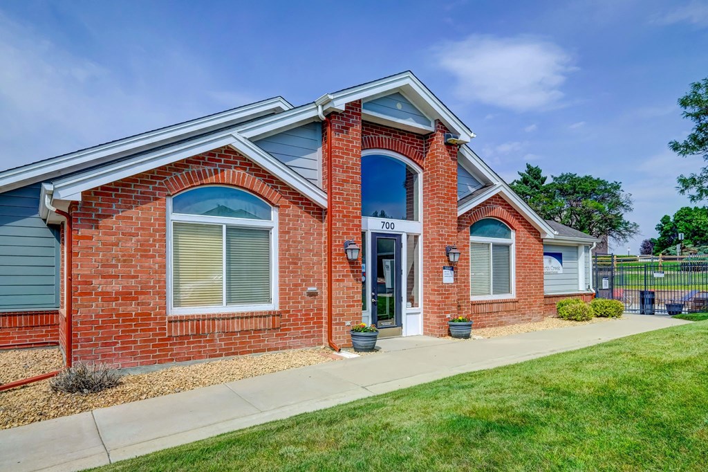 the front of a brick house with a sidewalk and grass