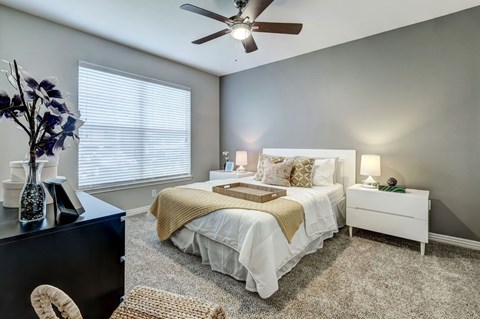 A bedroom with a white bed and a ceiling fan.