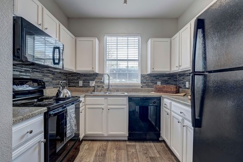 A kitchen with black appliances and white cabinets.