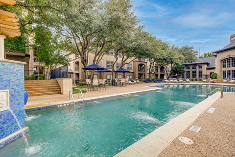 A swimming pool surrounded by trees and buildings.