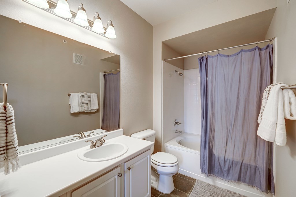 Bathroom with large vanity and lots of counter space, tub and shower combination, wood flooring