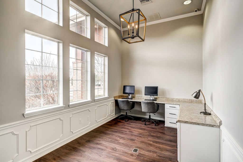 Business center with two computers, large windows and lots of desk space