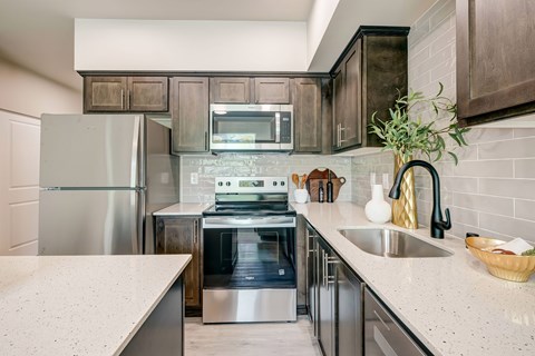 A modern kitchen with a stainless steel refrigerator and a double sink.
