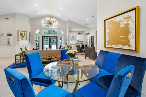 A dining room with blue chairs and a glass table.