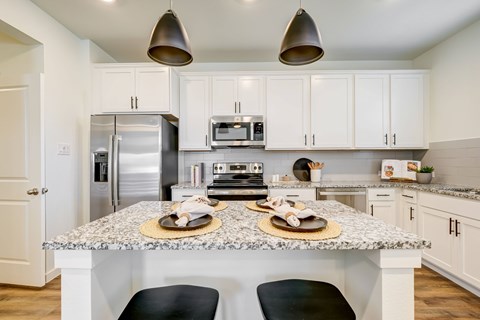 a kitchen with white cabinets and an island with black stools