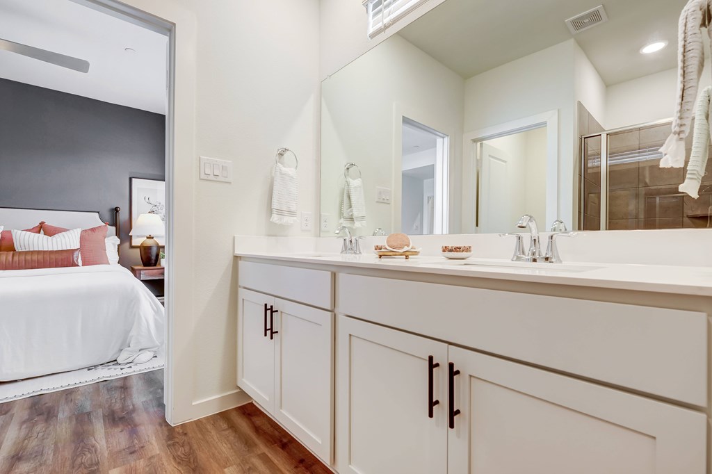 a bathroom with white cabinets and a large mirror with dual sink vanity