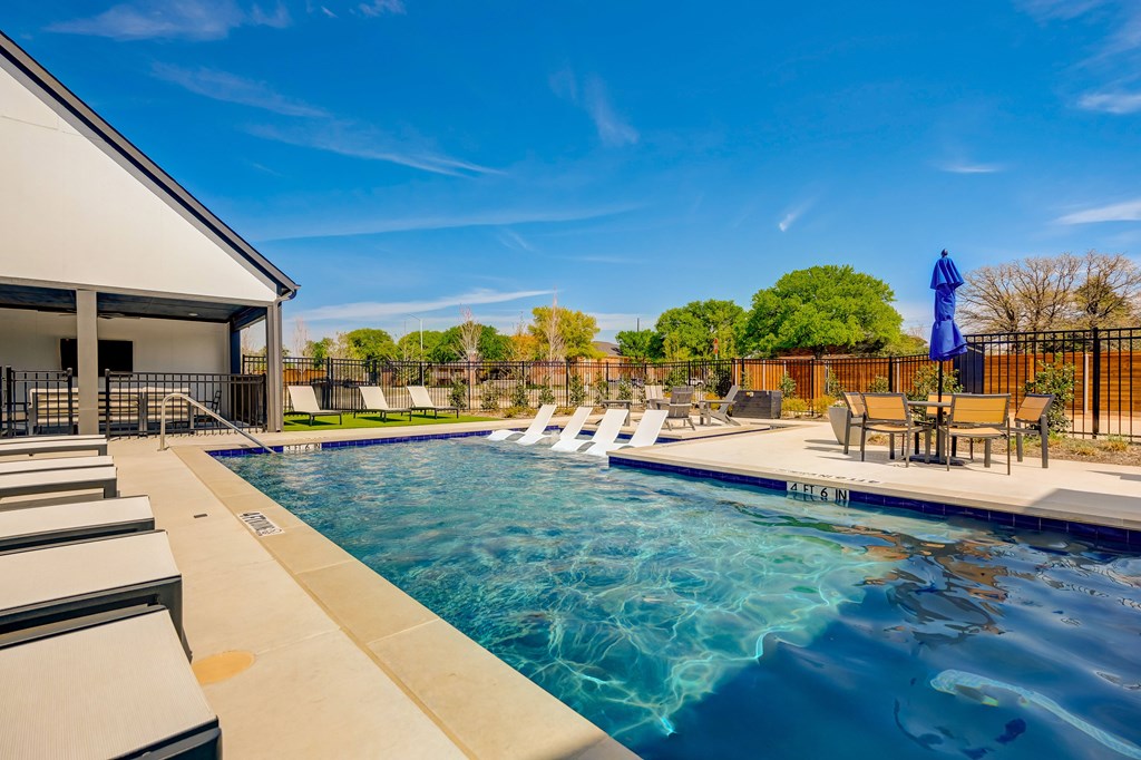 Sparkling gated pool with lounge chairs