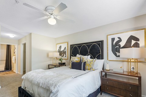 A bedroom with a bed, nightstand, and artwork on the wall.