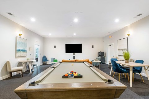 A pool table is in the middle of a room with a TV and a dining table.