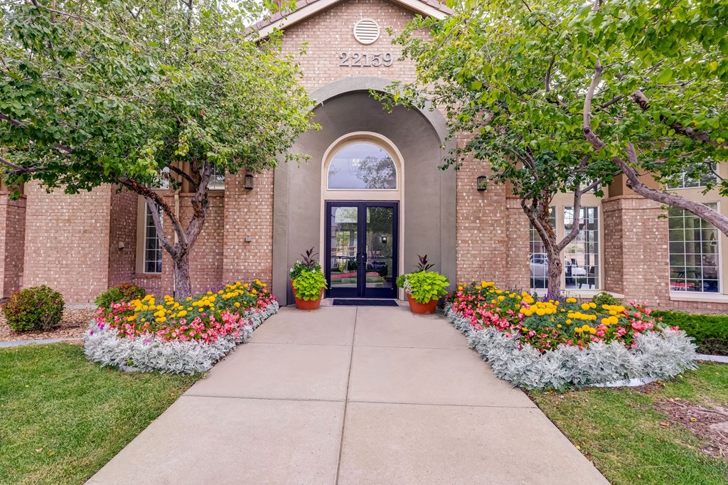 the front of a brick building with flowers and trees
