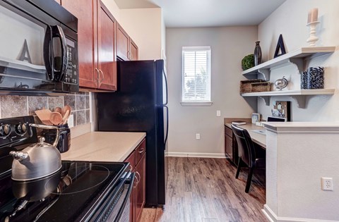 A kitchen with a black refrigerator and a black stove top oven.