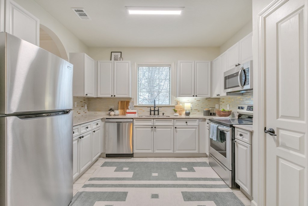 a white kitchen with stainless steel appliances and white cabinets