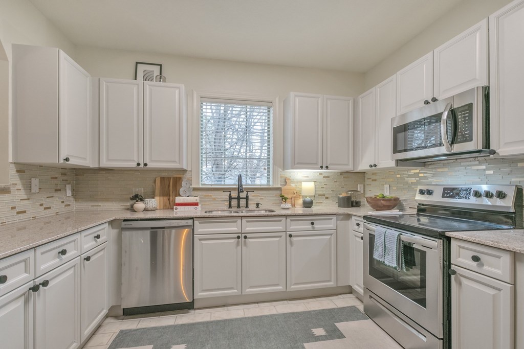 a kitchen with white cabinets and stainless steel appliances
