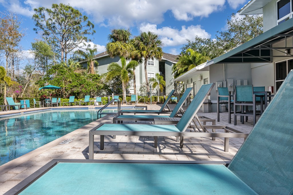 a pool with lounge chairs and a poolside house with a pool