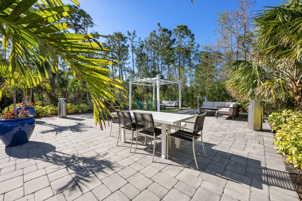 a patio with a table and chairs and palm trees