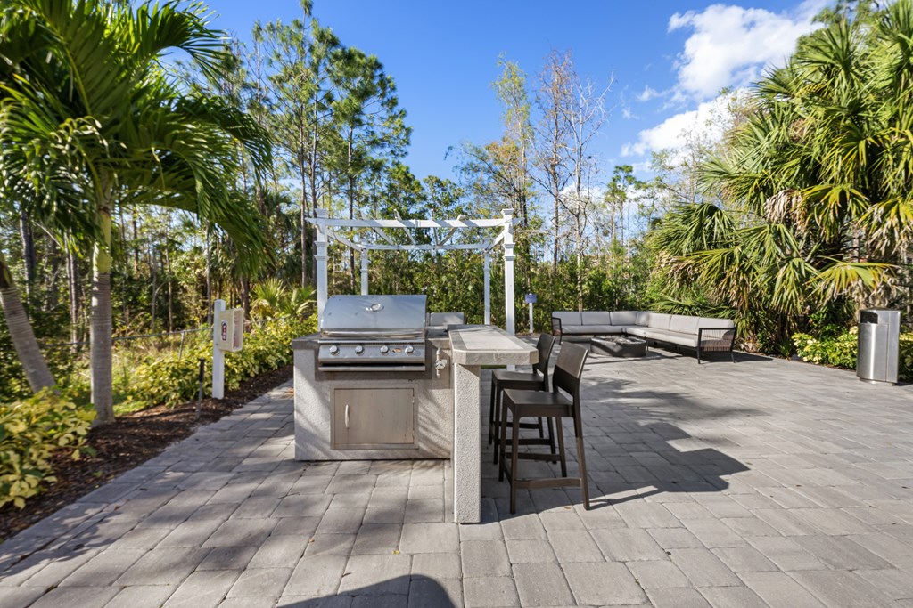 a patio with a grill and a table with chairs