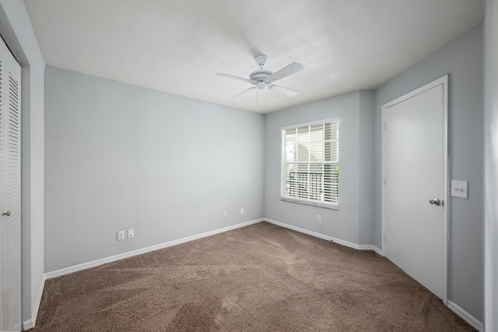 an empty room with carpet and a ceiling fan