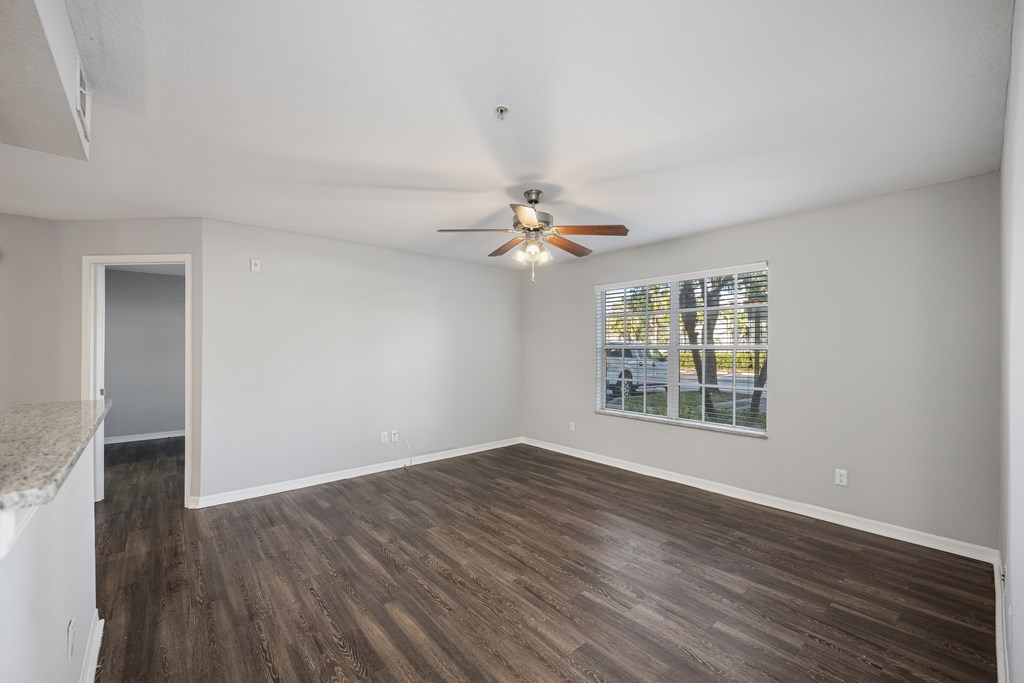 an empty living room with a ceiling fan and a window