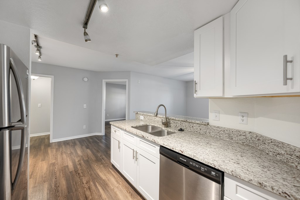 a kitchen with white cabinets and granite counter top and stainless steel appliances