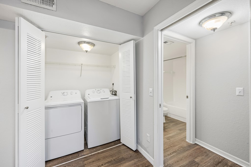 a white laundry room with two washes and a dryer