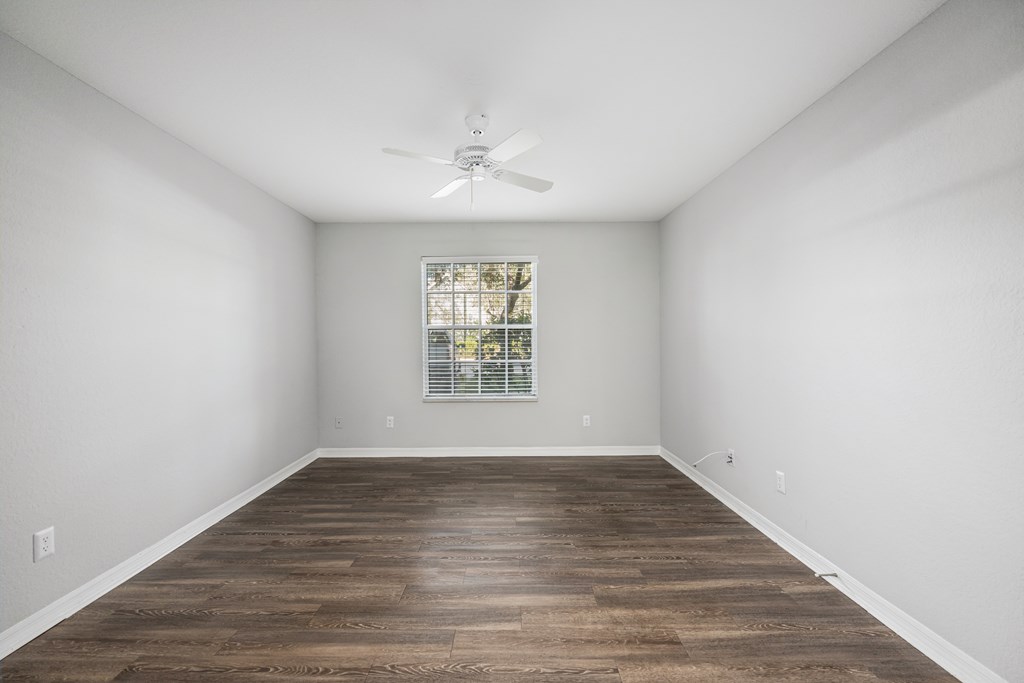 an empty room with white walls and a ceiling fan