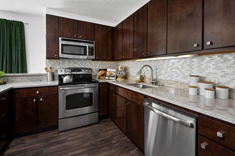 A kitchen with dark wood cabinets and a stainless steel dishwasher.