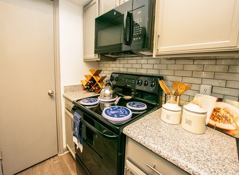 A kitchen with a black stove top and a black microwave above it.