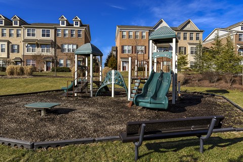 A playground with a green slide and a wooden swing set.