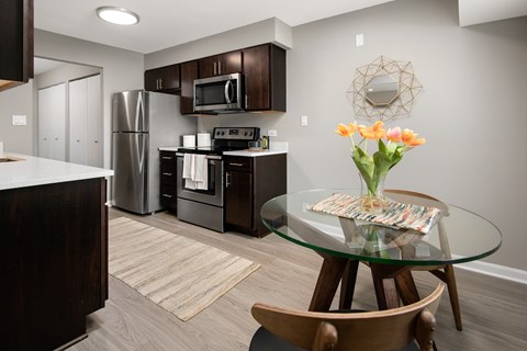 A kitchen with a glass table and a vase of flowers.