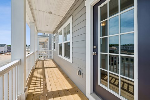 A balcony with a white railing and a wooden floor.